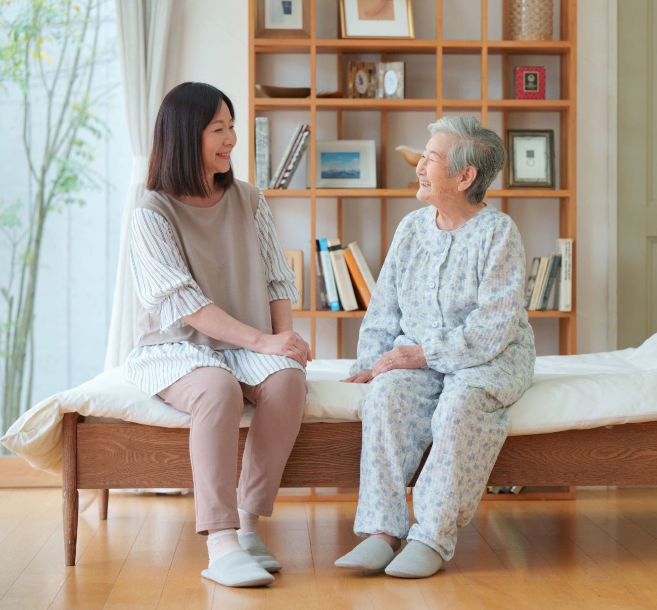 自宅のベッドサイドで穏やかな表情で向き合うご利用者様と付き添いの方